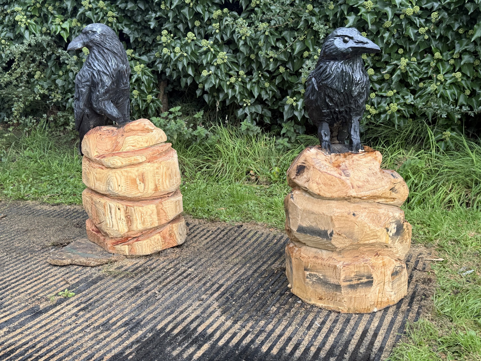 Pair of carved ravens on stumps — chainsaw carving by Woodaknot chainsaw carving & sculpting