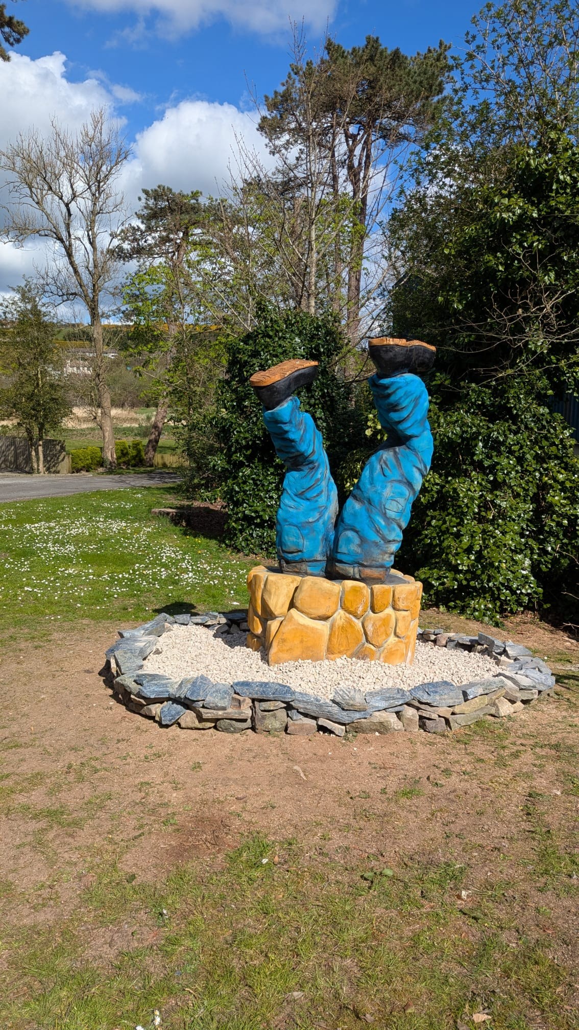 upside-down figure legs in well sycamore stump renovation — chainsaw carving by Woodaknot chainsaw carving & sculpting