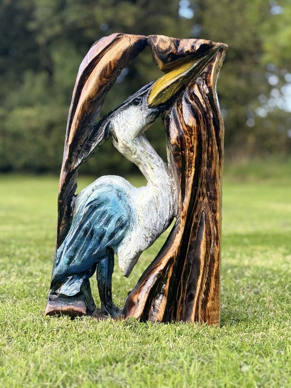 Heron emerging from a carved trunk — chainsaw carving by Woodaknot chainsaw carving & sculpting