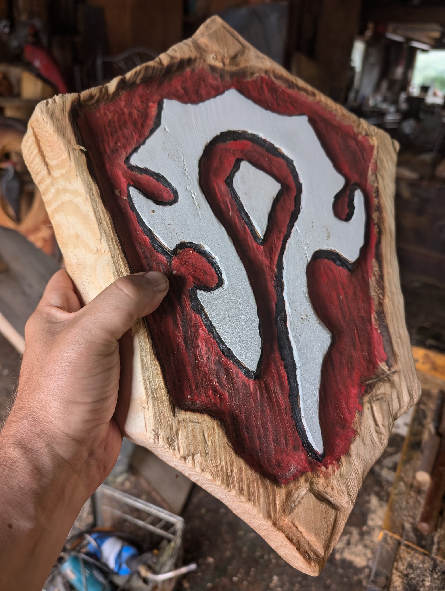 carved shield plaque with stylized white emblem — chainsaw carving by The Grateful Tech